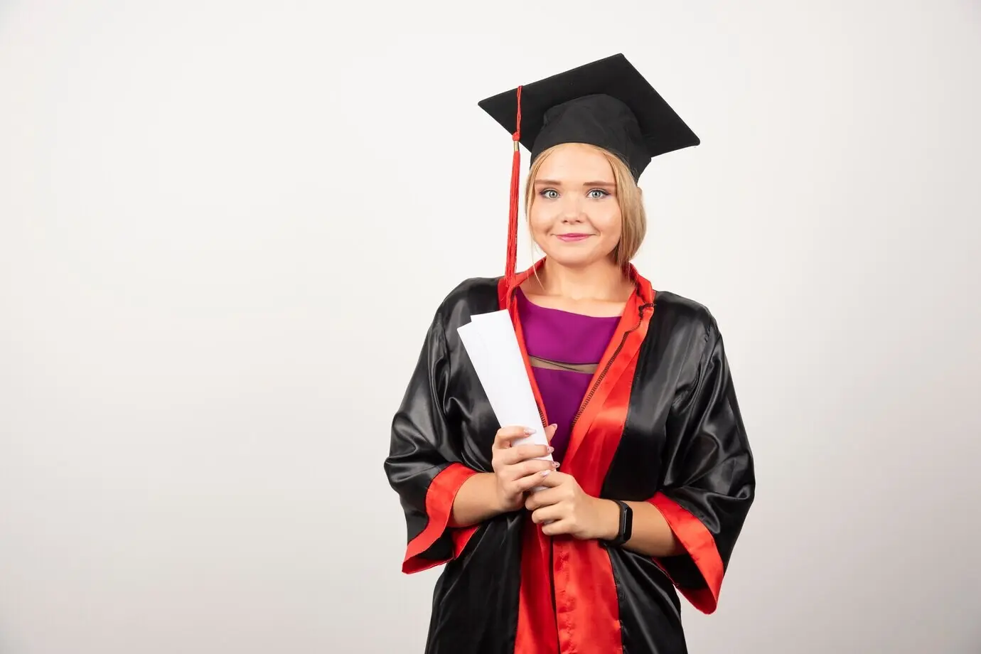 Schöne Studentin im Talar hält ein Diplom.